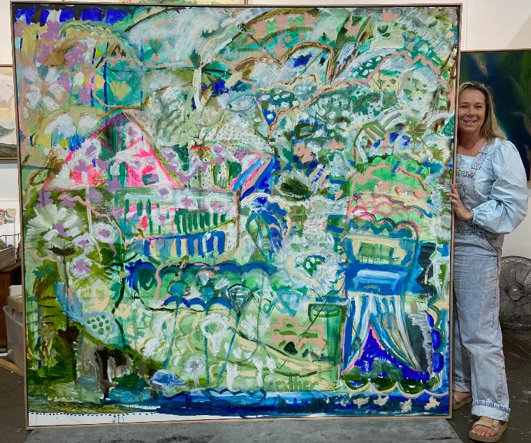 Artist Jay Feather standing with one of her framed artworks